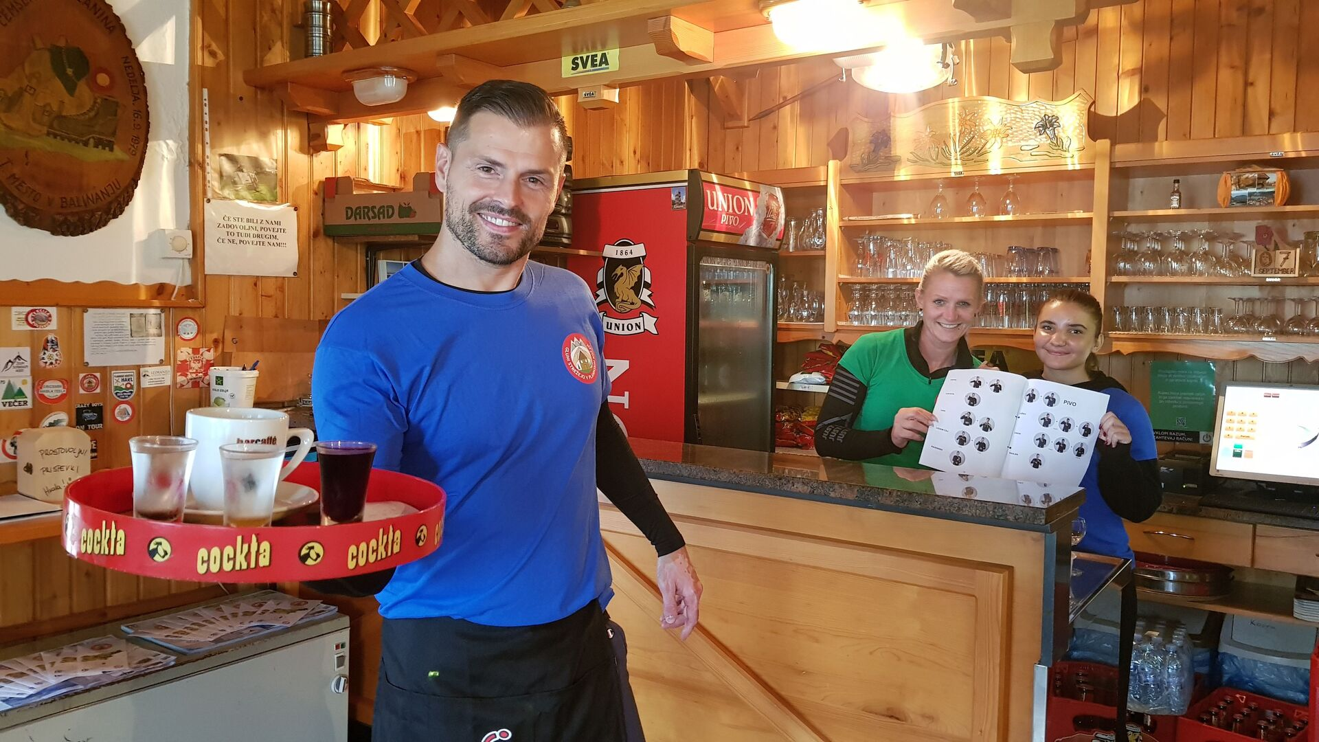 Na sliki natakar s polnim pladnjem pijač in dve prostovoljki s prilagojenim jedilnim listom v akciji GSPK, foto arhiv GSPK